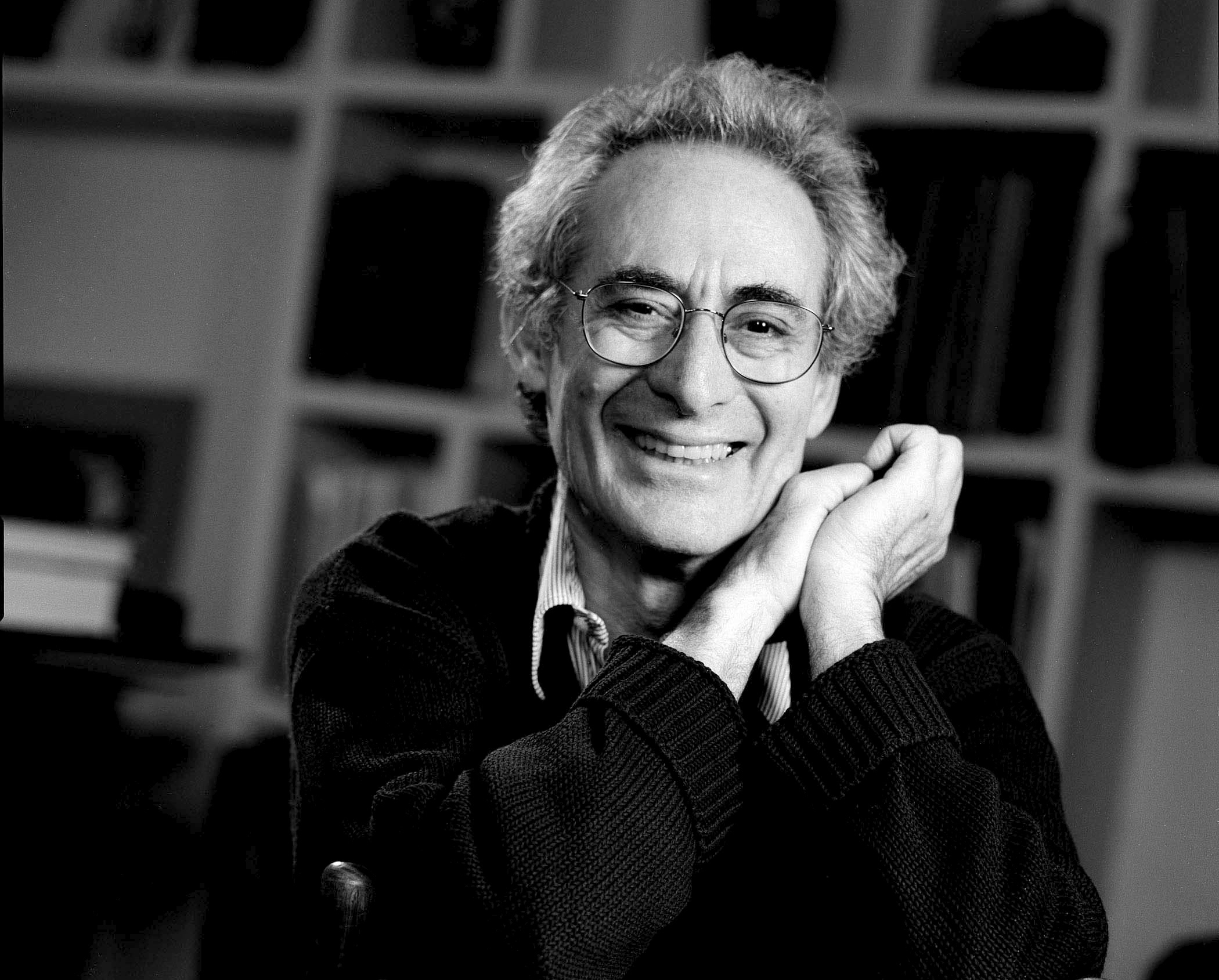 A black and white headshot of an older man smiling at the camera.