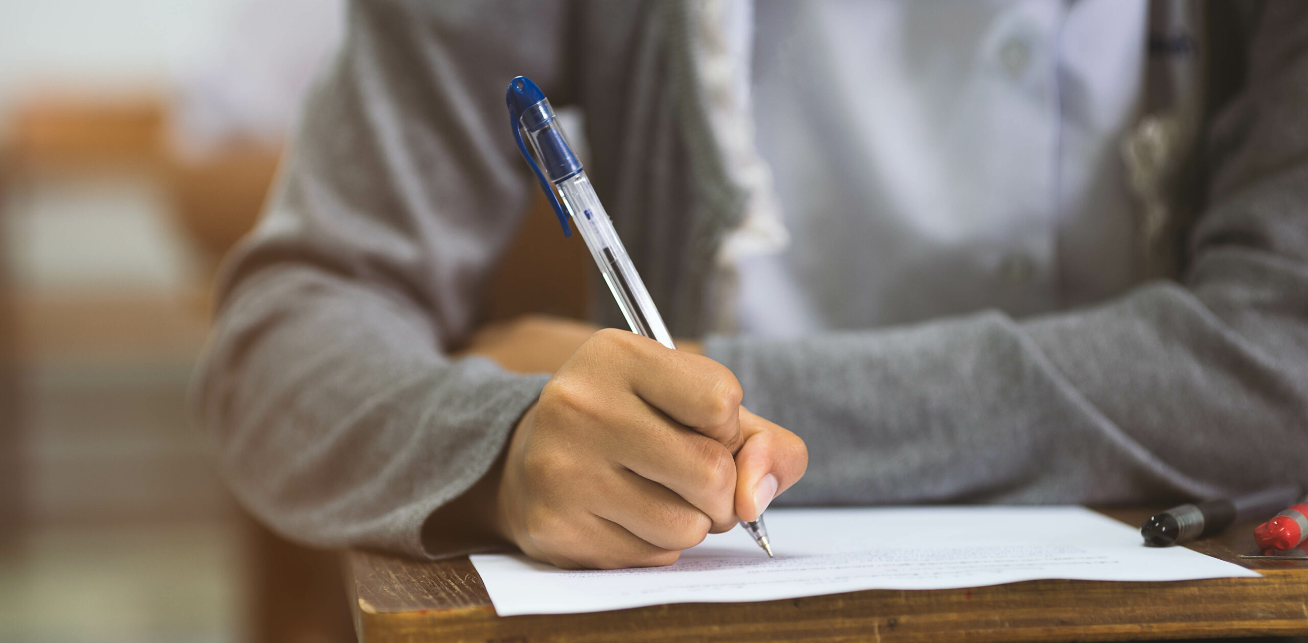 A closeup of ahand holding a pen and writing on a piece of paper.