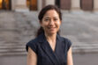 A chest-up photo of Harvard math professor Lauren Williams standing in front of building stairs wearing a sleeveless navy top.